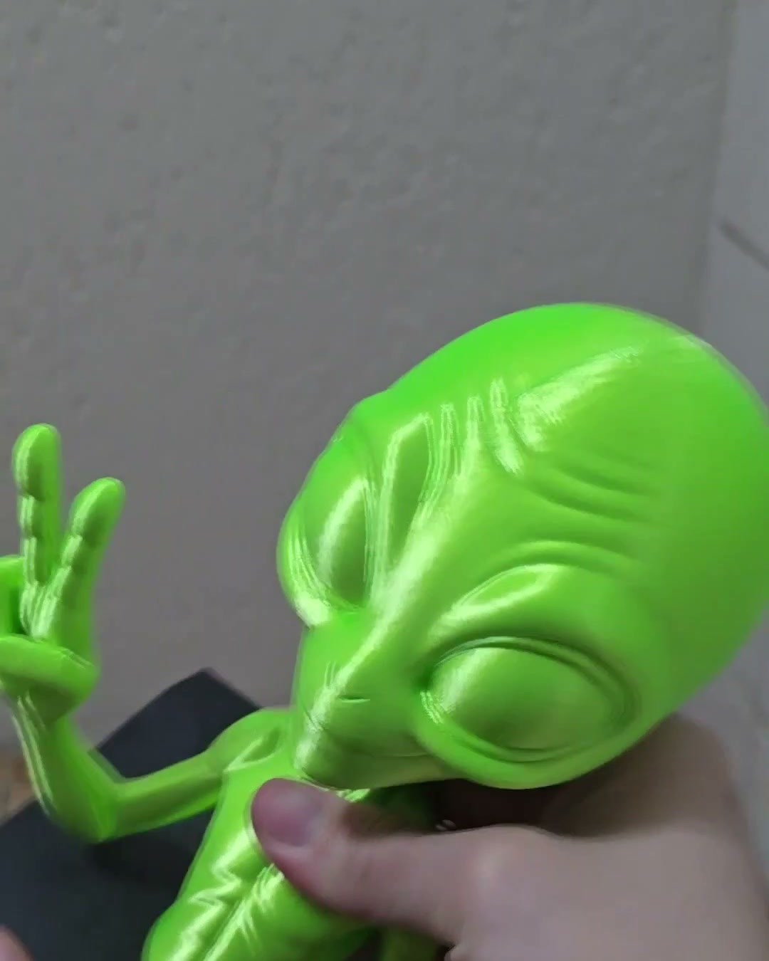 Close do rosto do alien neon impresso, com a mão na pose de paz e amor