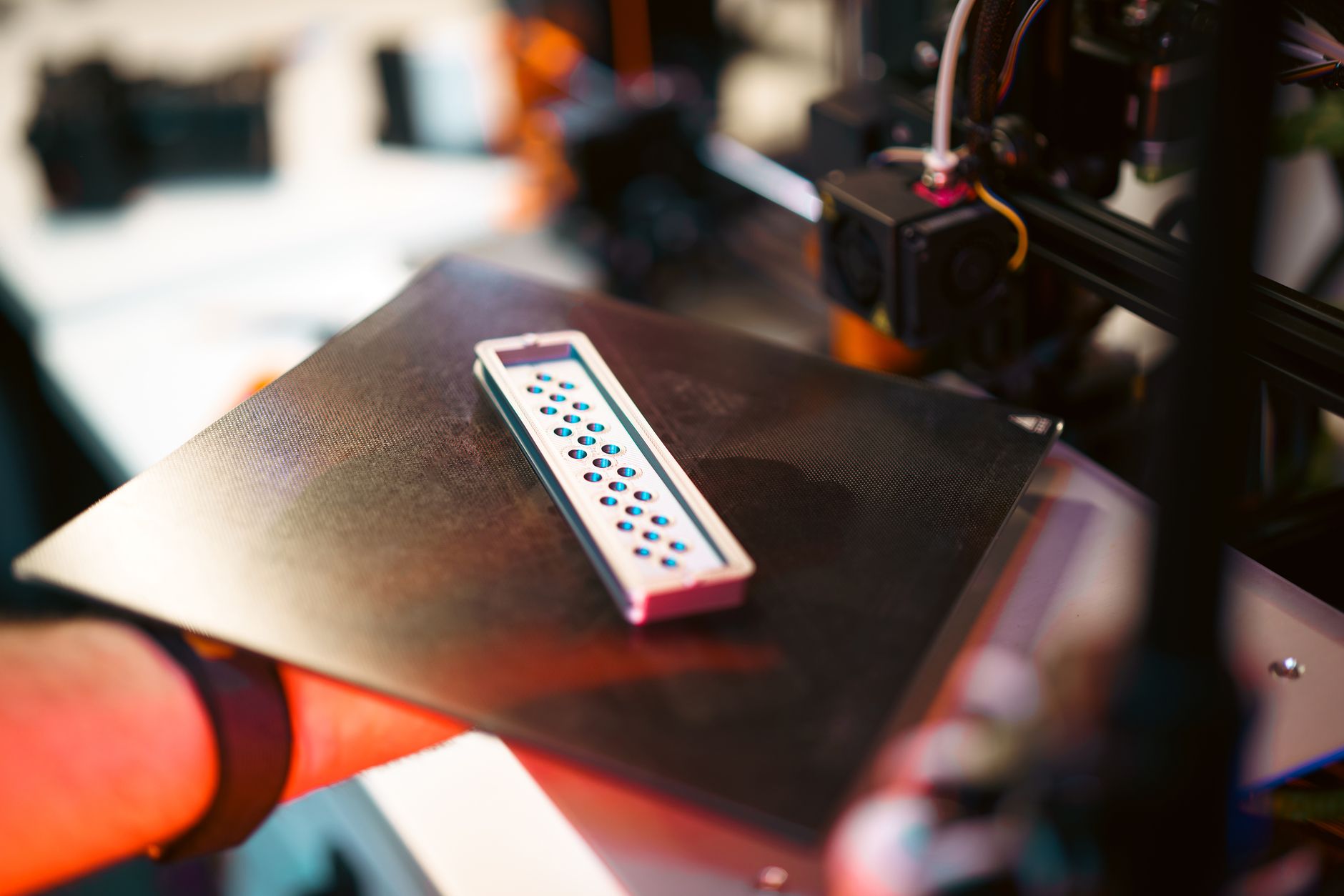 Bico de impressora 3D extrudando filamento em detalhe, com iluminação de LED