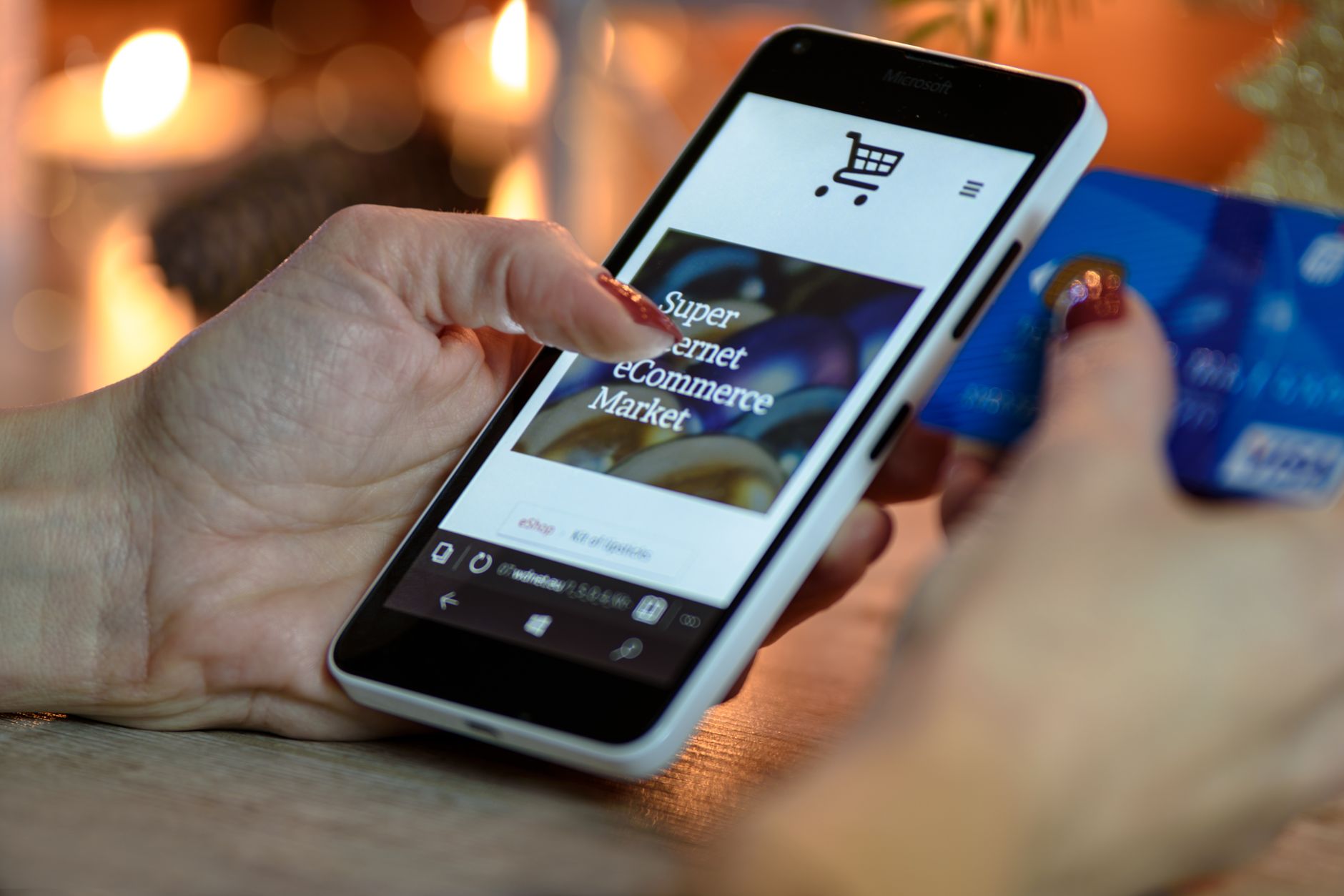Pessoa comprando em marketplace pelo celular com cartão na mão