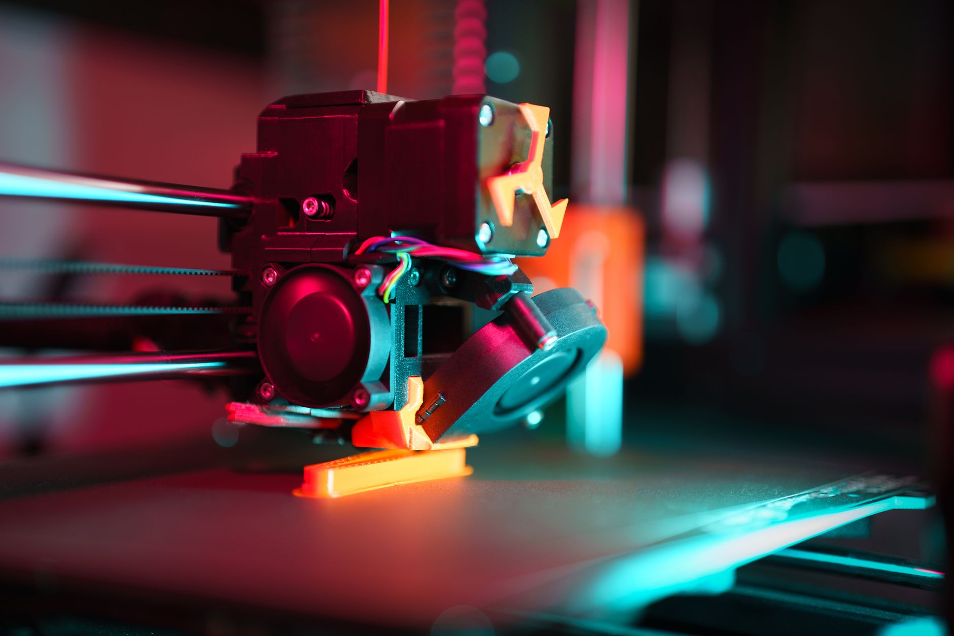 Impressora 3D FDM imprimindo uma peça branca em cima da mesa de trabalho, com filamento passando pela extrusora